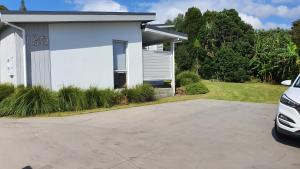 a white house with a driveway in front of it at Whangapoua waves in Whangapoua +18 photos