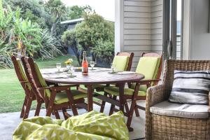 a patio table with chairs and a bottle of wine at Whangapoua waves in Whangapoua