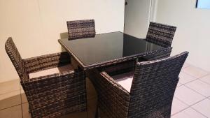 a table with three chairs and a glass top at Merika Sweet Home in Orufara