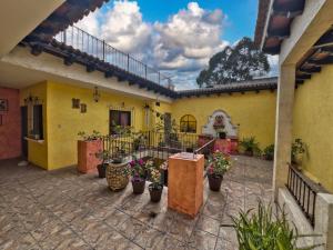 a courtyard of a yellow building with potted plants at Maison Bougainvillea in Antigua Guatemala