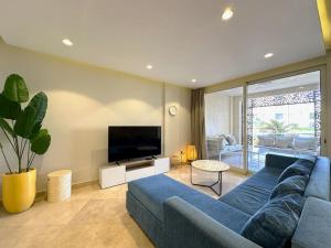 a living room with a blue couch and a flat screen tv at Chic 3BR Ground Free Beach & Pool access at Mangroovy in Hurghada