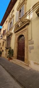 a building with a large wooden door on a street at 35 Rooms Palazzo Buoninsegni in Colle Val D'Elsa