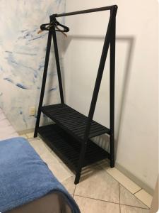 a black shelf next to a bed in a room at Quarto próximo a vila germânica in Blumenau