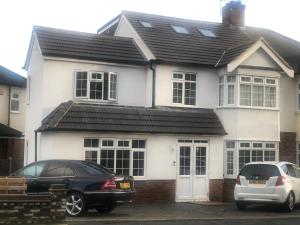 zwei Autos, die vor einem weißen Haus geparkt sind in der Unterkunft Comfy En-suite King Size room in Hornchurch