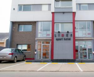 a building with a car parked in a parking lot at Links Apart Hotel in Río Grande