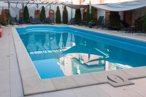 a blue swimming pool with chairs and umbrellas at Red Clay Apartments City Club in Belgrade