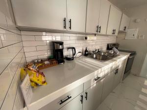 a kitchen with white cabinets and a sink at Relaxing Retreat for 5 Close to Beach & Airport in Carolina +4 photos
