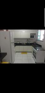 una cucina con frigorifero bianco e pavimento piastrellato bianco di Apartamento Premium Praia do Forte a Cabo Frio Altre 9 foto