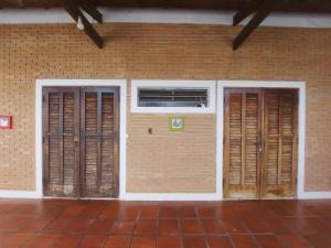 a brick building with two doors and a window at SUÍTES NA PRAIA DO ITAGUÁ conchegouba in Ubatuba
