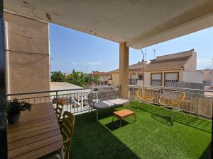 a balcony with chairs and a table and grass at Apartamento con terraza cerca del mar in Torre de la Horadada