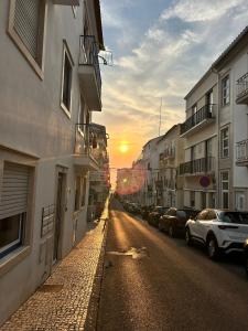 Una calle vacía con coches aparcados al costado de un edificio. en Marilaura's beach house, en Nazaré