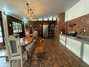 a kitchen with a wooden table and a refrigerator at Refúgio Natural com Praia Paradisíaca a 300m in Matinhos