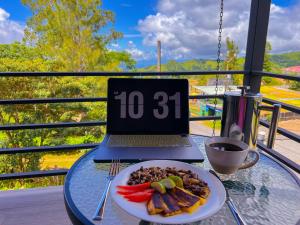 a plate of food on a glass table with a laptop at Monstera Apartments Monteverde in Monteverde Costa Rica +23 photos