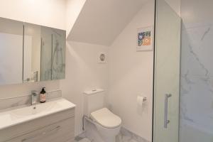 a white bathroom with a toilet and a shower at Modern 2 Bedroom Townhouse in CBD With Parking! Sleeps 5 in Christchurch +28 photos