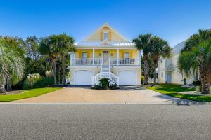a large yellow house with palm trees in front of it at 1 Mi to Beach and Hot Tub Murrells Inlet Retreat! in Myrtle Beach