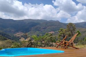 a pool and a chair on a deck with mountains in the background at Mini Casa in Baependi