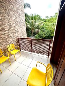 a balcony with yellow chairs and a view of trees at Casa aconchegante em Lençóis in Lençóis