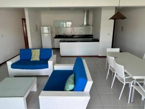 a living room with blue and white furniture and a kitchen at Apartamento 03 suítes - Tree Bies Beach Resort - Praia de Subaúma in Entre Rios