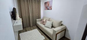 Una sala de estar con un sofá y un televisor. en Apartamento Temporada Barra-Vento, en Guriri