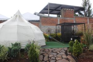 a white tent in a garden with a building at El Mirador Family Glamping TIENDA ÁRABE in Estancia de Itargua