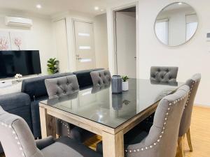 une salle à manger avec une table et des chaises en verre dans l'établissement D112 Braybrook Central Stay-Great Getaway, à Braybrook