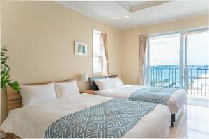 two beds in a hotel room with a large window at  M’sOceanⅡ Uruma in Uruma