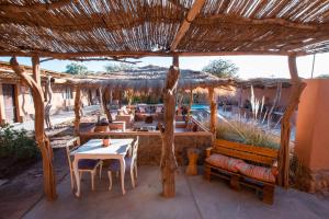 a patio with a table and chairs and a straw umbrella at Hotel Pat'ta Hoiri in San Pedro de Atacama
