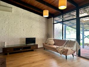 Una sala de estar con un sofá y un televisor en Tranquil home in hills with city views, en Greenmount