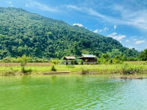 a house next to a lake with a mountain at Ba Be Retreat in Bak Kan