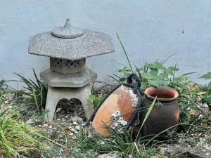un bagno di pietra nell'erba vicino a un muro di 漁師宿三浦屋秀栄丸 a Shōdoshima