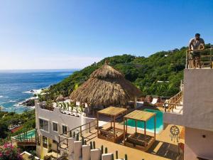 Ein Mann steht auf einem Gebäude mit Blick auf das Meer in der Unterkunft Xeno Hotel Boutique in Playa Estacahuite