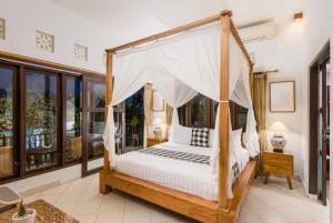 a bedroom with a canopy bed in a room at Umah Bali Villa in Ubud