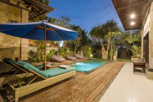 ウブドにあるUmah Bali Villaの青いパラソル、椅子、ソファ、パラソル付きのスイミングプールを提供しています。