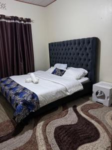 a bedroom with a bed with a black headboard at g and m luxe Abode in Nyeri