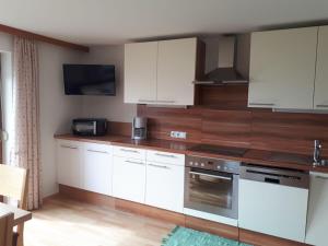 a kitchen with white cabinets and a stove top oven at Winterstaude Comfortable holiday residence in Großdorf