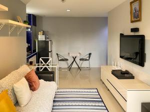 a living room with a couch and a tv at Cozy 1br walk to BTS and Airport Rail Link Close to Malls 11 in Bangkok