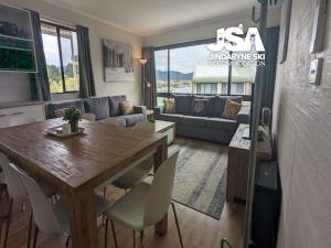 una sala de estar con una mesa y un sofá en Alpine Mountain View 40, en Jindabyne