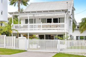a white house with a white picket fence at Barra Luxe Beach House in Yaroomba