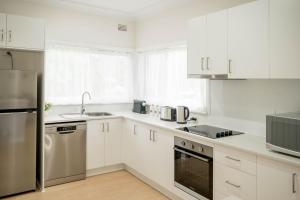 una cucina con armadi bianchi e frigorifero in acciaio inossidabile di Tamworth Country Stay on Goonoo a West Tamworth Altre 6 foto