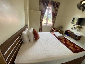 una habitación con una cama grande con sábanas y almohadas blancas en Sky Hotel MC - by BAY LUXURY, en Mộc Châu 2 fotos más