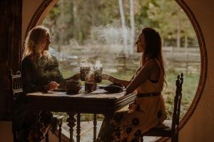 two women sitting at a table in front of a mirror at Hobbit house in Tīnūži