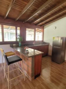 a kitchen with a counter and a refrigerator at La Pascana Ecolodge frente al parque Arví Entorno natural excepcional, reserva natural, áreas protegidas, conexión con la naturaleza y avistamiento de aves a 3km del metrocable Guarne in Guarne