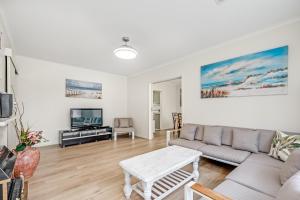 a living room with a couch and a tv at Jetty Road Retreat - Brighton - C21 SouthCoast Holidays in Brighton