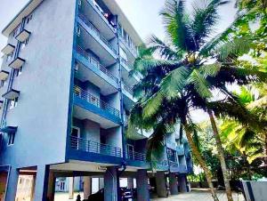 a tall building with palm trees in front of it at The Cider 1bhk Apartment Goa - Sleeps 4 in Palolem