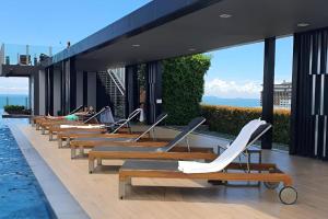 una fila de tumbonas en un edificio con piscina en Sea View Condo 29F Central Pattaya & Rooftop Pool, en Pattaya central