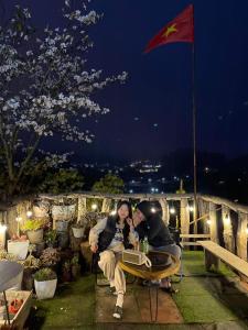 two people are sitting at a table at night at Đồi Thông Homestay Mộc Châu - by BAY LUXURY in Sơn La +10 photos