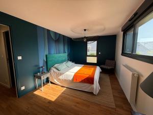 ein Schlafzimmer mit einem Bett in einem Zimmer mit blauen Wänden in der Unterkunft Les Palmiers in Regnéville-sur-Mer