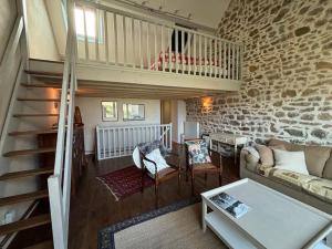 ein Wohnzimmer mit einer Treppe und einer Steinmauer in der Unterkunft Les Palmiers in Regnéville-sur-Mer