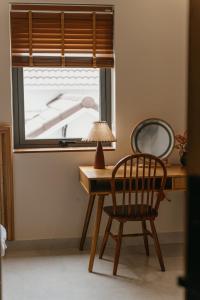 einen Schreibtisch mit einem Stuhl, einer Lampe und einem Fenster in der Unterkunft Creme Homestay Đà Lạt in Khu Chi Lăng