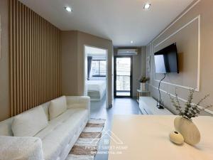a living room with a white couch and a tv at Tower condo Rawai Phuket in Ban Klang